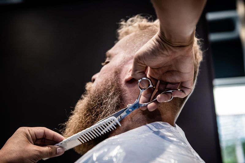 Beard being sculpted with scissors and comb